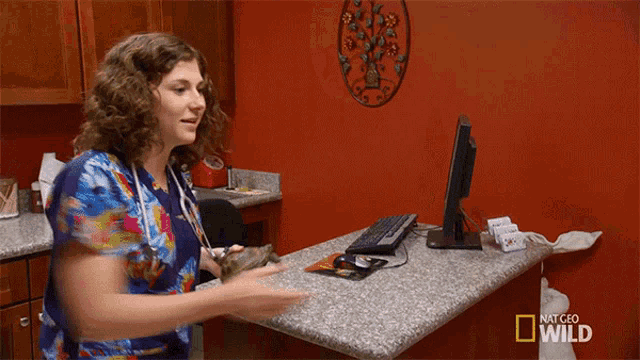 a woman stands in front of a computer screen that says national geographic wild on it