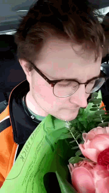 a man wearing glasses is holding a bouquet of pink flowers and a piece of paper that says erick on it
