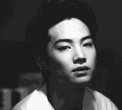 a black and white photo of a young man 's face with a serious look on his face .
