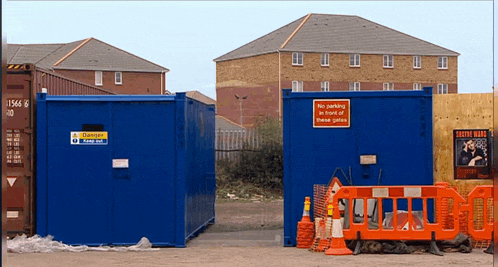 a blue building with a sign on it that says " no parking in front of these gates "