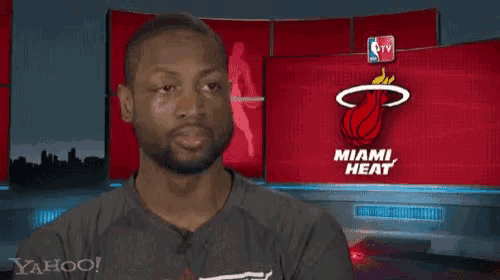 a man is standing in front of a miami heat sign