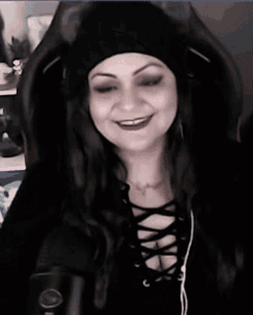 a woman wearing a black hat and headphones is sitting in front of a black microphone