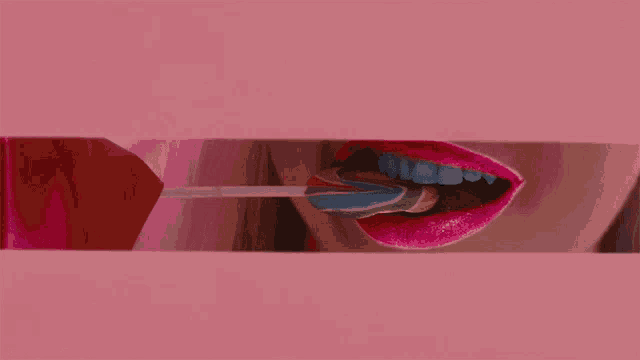 a woman with pink lips is licking a lollipop in her mouth