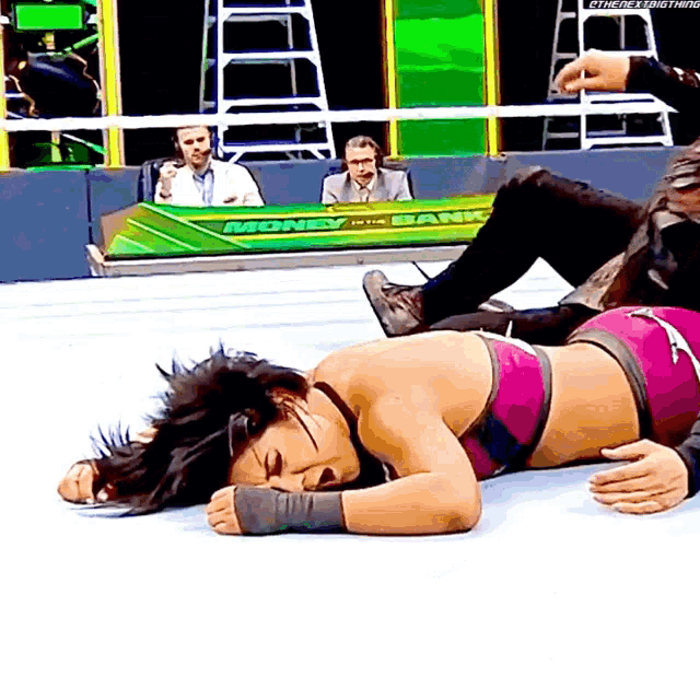 a woman is laying on the ground in front of a money in the bank sign