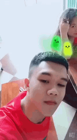 a man in a red shirt is sitting next to a woman with a green smiley face on her arm