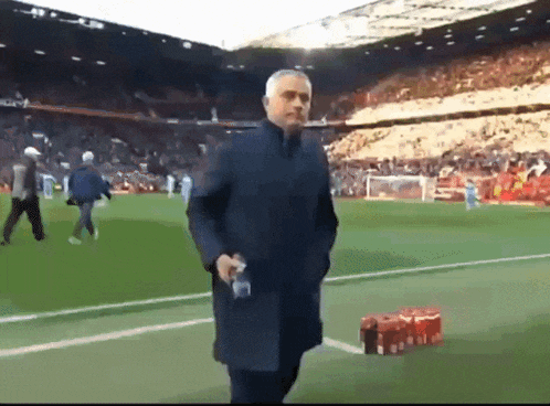 a man walking on a soccer field with a bottle of water