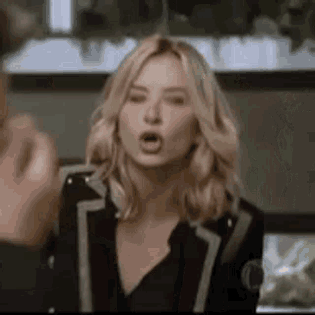 a woman in a black jacket is talking to a man in a room .
