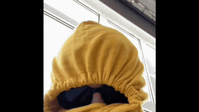 a person wearing a yellow hoodie and black sunglasses .