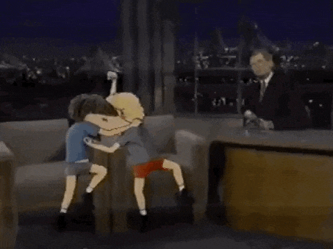 two cartoon characters are hugging each other on a couch while a man looks on .