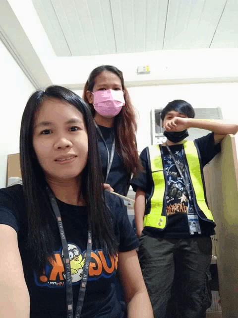 a woman wearing a t-shirt that says ' x ' on it poses with two other people