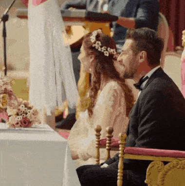 a bride and groom sitting at a table with flowers
