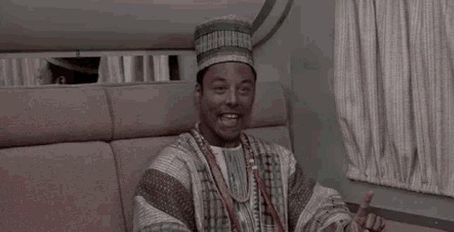 a man in a hat is sitting on a couch and laughing while saying `` happy new year '' .