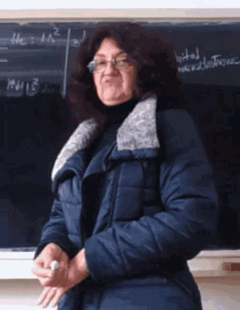 a woman stands in front of a blackboard with numbers on it including a2