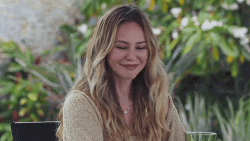 a woman is smiling while sitting at a table with a glass of wine