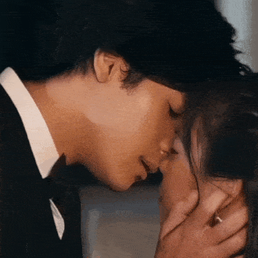 a man in a suit kisses a woman on the forehead