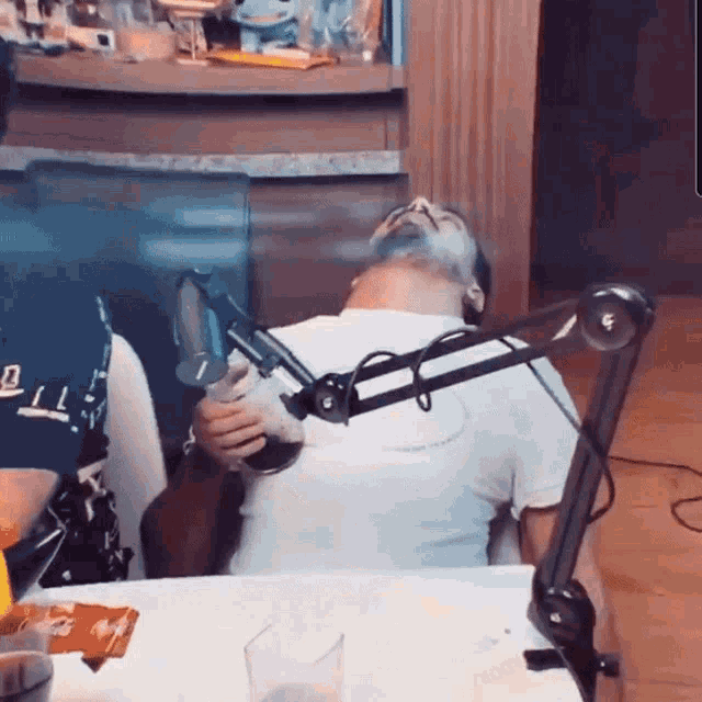 a man with a beard is sitting at a table with a microphone in front of him