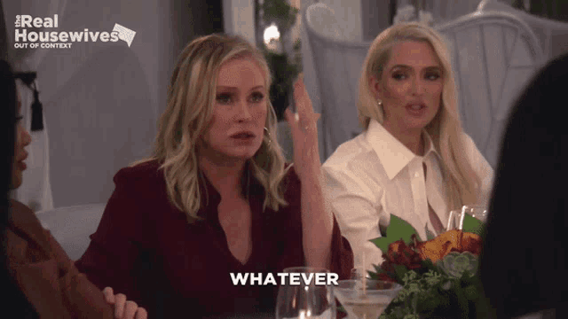 two women sit at a table with a real housewives logo in the background