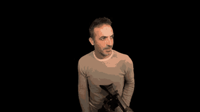 a man is holding a camera and scratching his head .