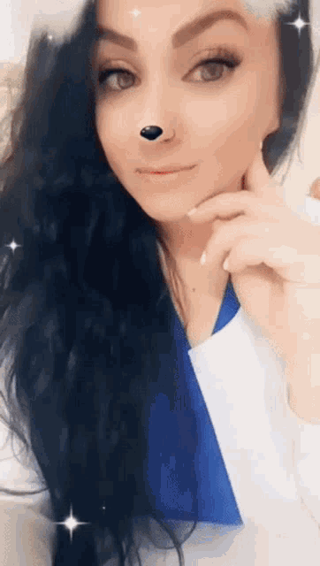 a woman with long black hair and a nose ring looks at the camera