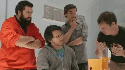 a group of men are standing around a table in front of a sign that says studios