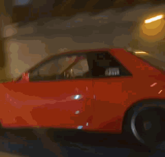 a red sports car is driving down a road at night