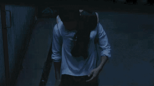 a man and a woman are hugging each other in the dark .