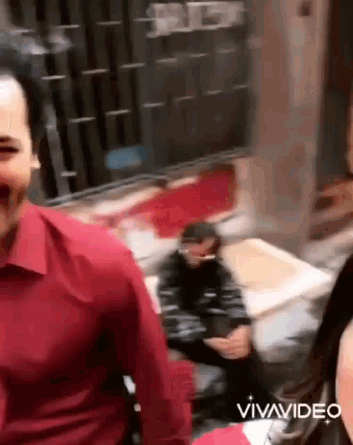 a man in a red shirt is standing next to a woman in a black jacket and a man in a black jacket .