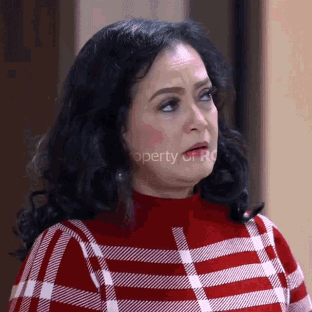 a woman wearing a red and white plaid sweater is standing in front of a sign that says " property of ro "