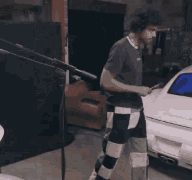 a man in a supreme shirt stands in front of a white car