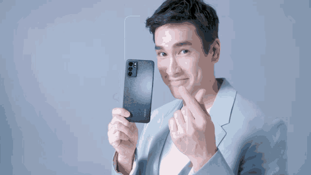 a man in a suit is holding a black oppo phone