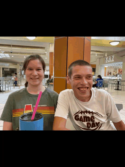 a man wearing a game day shirt smiles next to a woman