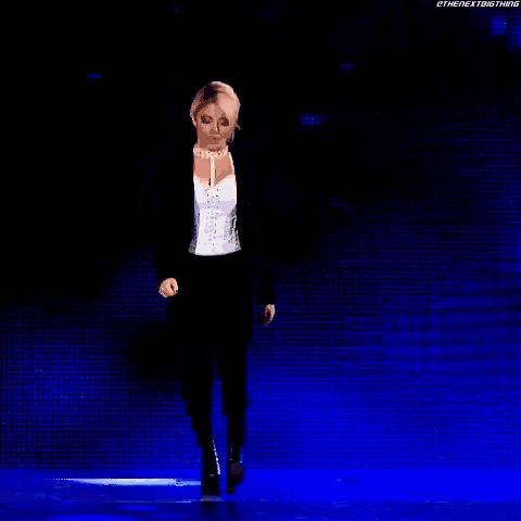a woman in a black jacket and white top is dancing on a stage .