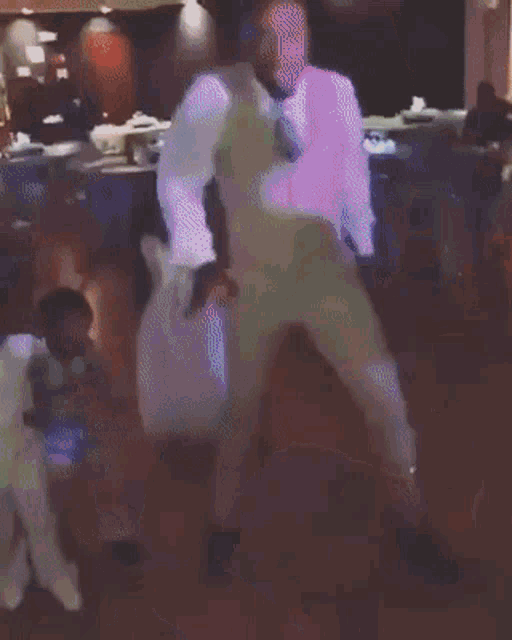 a man in a white suit is dancing in a dark room .