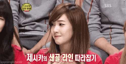 a woman is sitting in front of a group of people with korean writing on the screen .