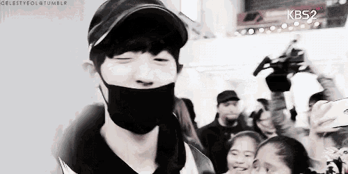 a man wearing a black mask and a hat is standing in front of a crowd with kbs2 written on the bottom right
