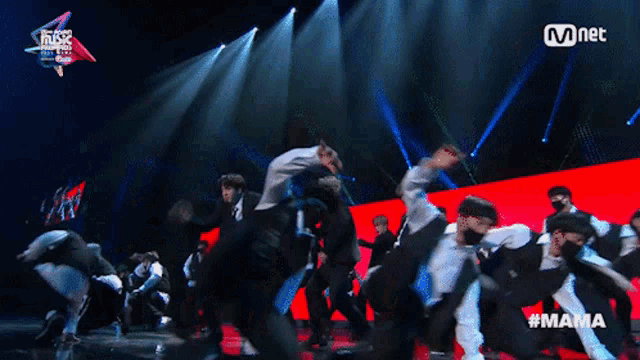 a group of people are dancing on a stage with a mnet logo behind them