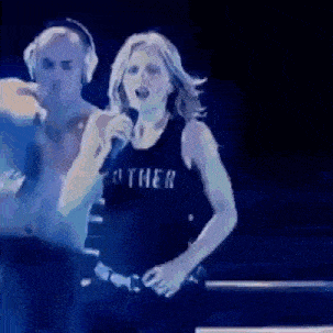 a woman singing into a microphone wearing a shirt that says othei
