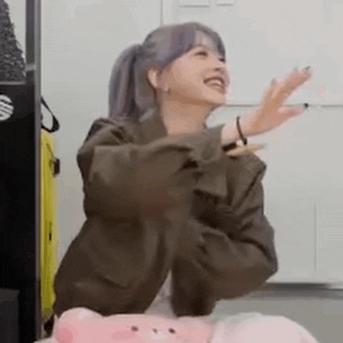 a woman is sitting on a pink pillow with her arms outstretched and laughing .