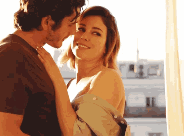 a man kisses a woman on the forehead while she smiles