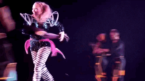 a woman in a futuristic outfit is dancing on stage