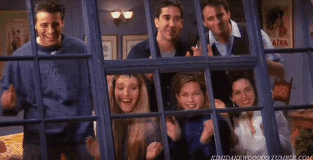 a group of people are standing in front of a window and smiling .