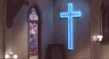 a church with a neon blue cross on the wall