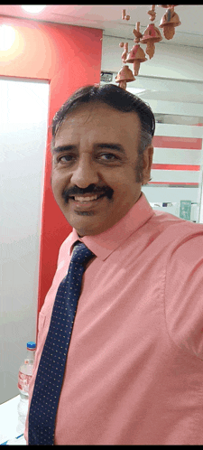 a man in a pink shirt and tie is smiling for the camera