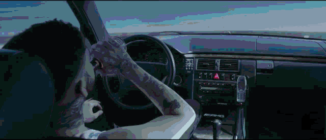 a man is driving a car with the word amg on the dash