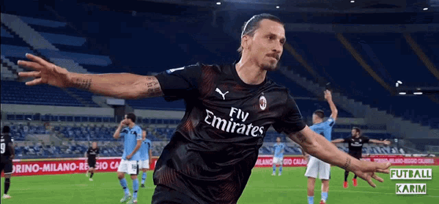 a soccer player wearing a fly emirates jersey celebrates his goal