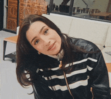 a woman wearing a black and white striped jacket is sitting on a couch