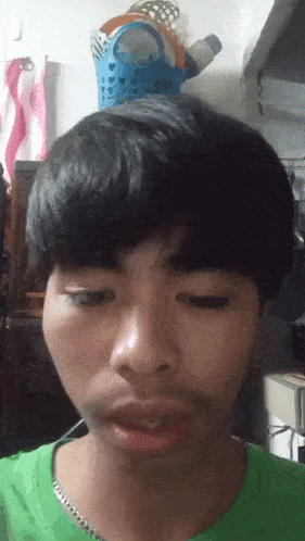 a young man in a green shirt is making a face