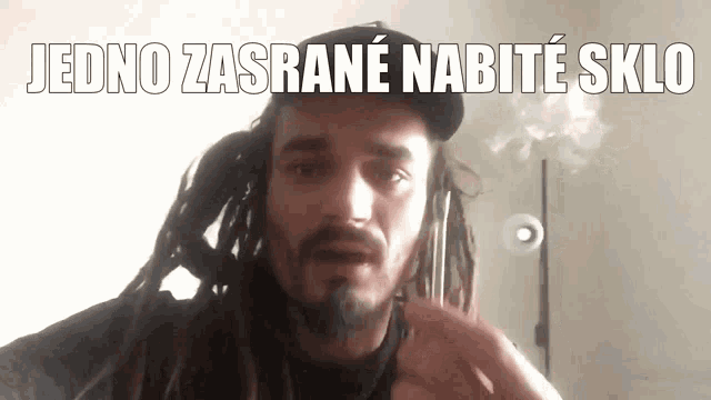 a man with dreadlocks and a beard has the words jedno zasrane nabite sklo written above him