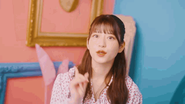a girl in a floral shirt is making a heart shape with her hands