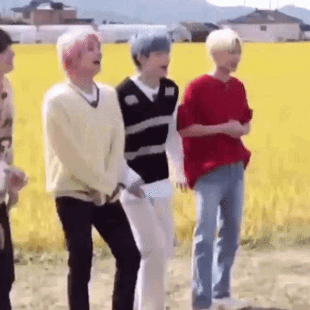 a group of young men are standing in front of a field .